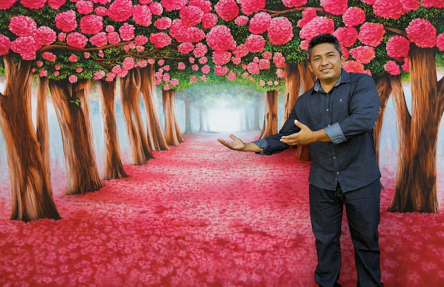 Caminho floral em perspectiva, com árvores e flores rosas e o artista à frente.