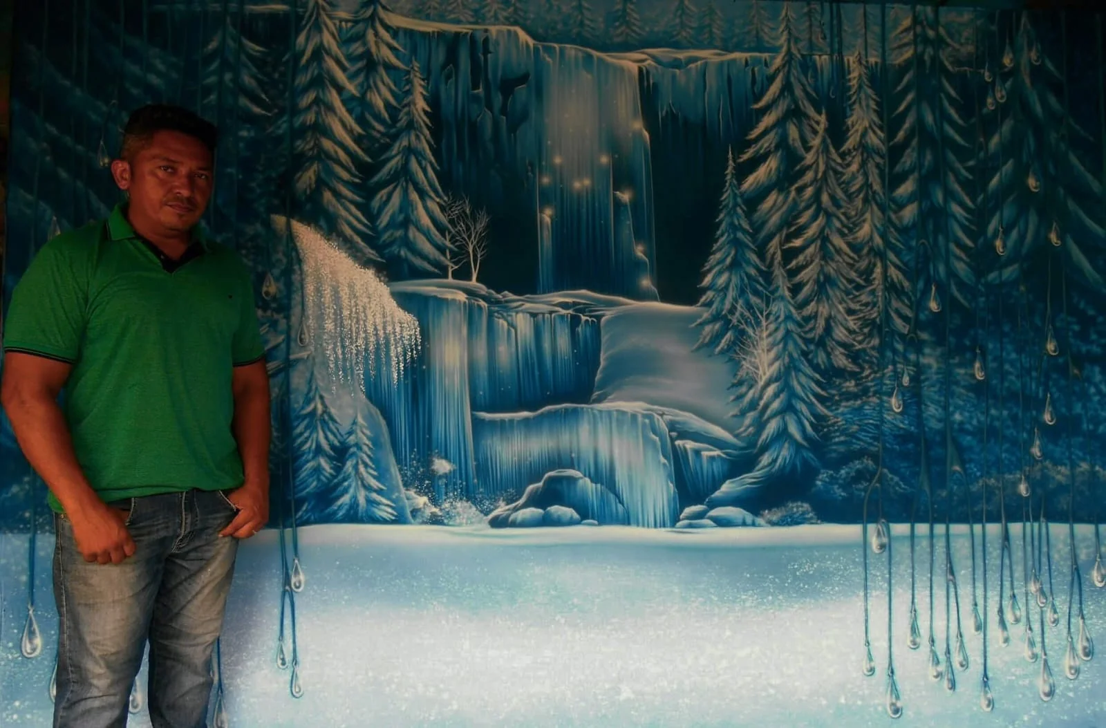Cenário de gruta gelada em tons de azul, com o artista à esquerda.