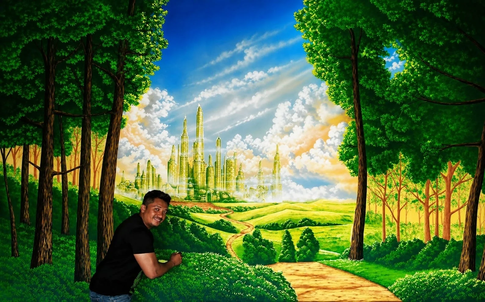 Paisagem de floresta com caminho iluminado e o artista junto ao mural.